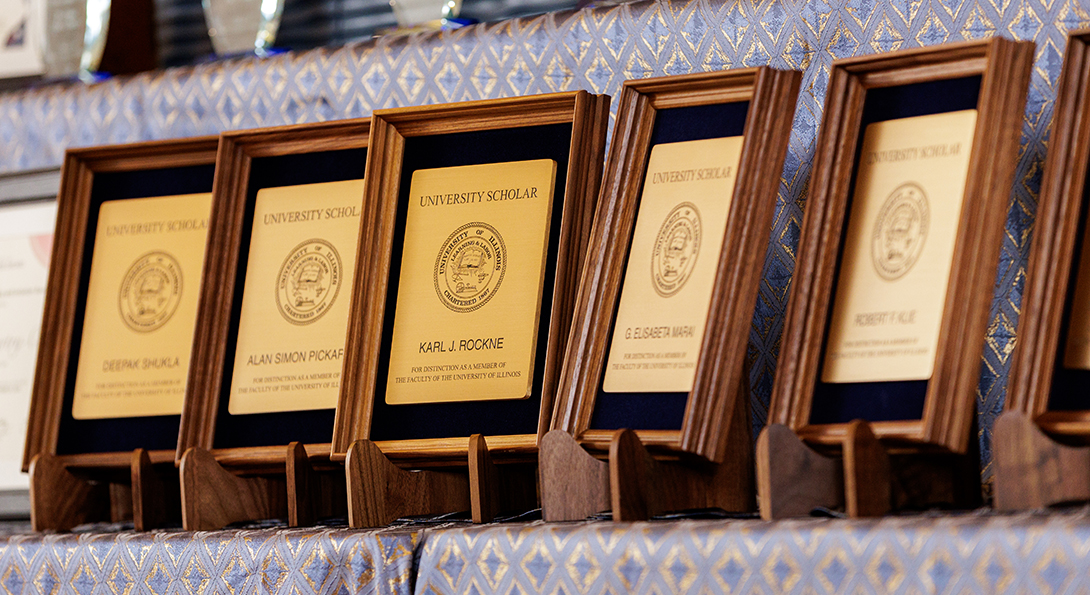 Five University Award plaques stand in a row, waiting to be awarded at the Faculty Awards Ceremony in the fall.