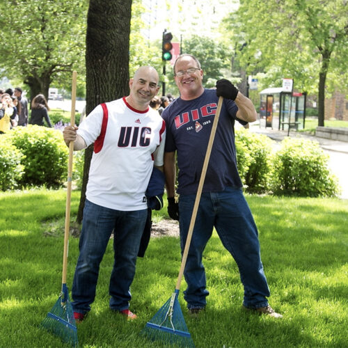 Two staff members participate in a campus cleanup.